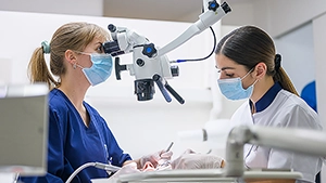 Dentistes réalisant des soins dentaires de précision à l’aide d’un microscope dans un cabinet dentaire moderne